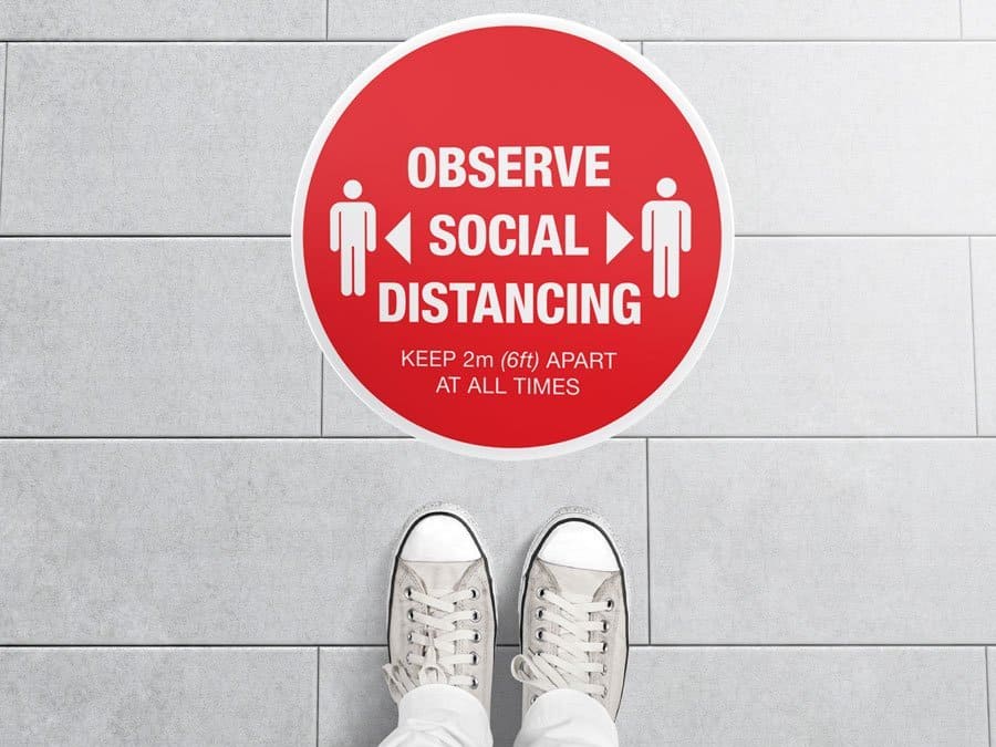 Round red Social Distancing Sticker that says "Observe Social Distancing" on tiles