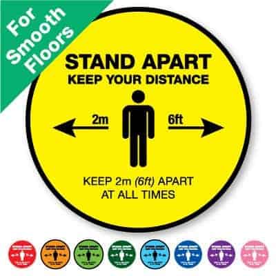 Round yellow Indoor Social Distancing Stickers for smooth floors that says "Stand apart keep your distance" on the top plus 8 other colours o the bottom