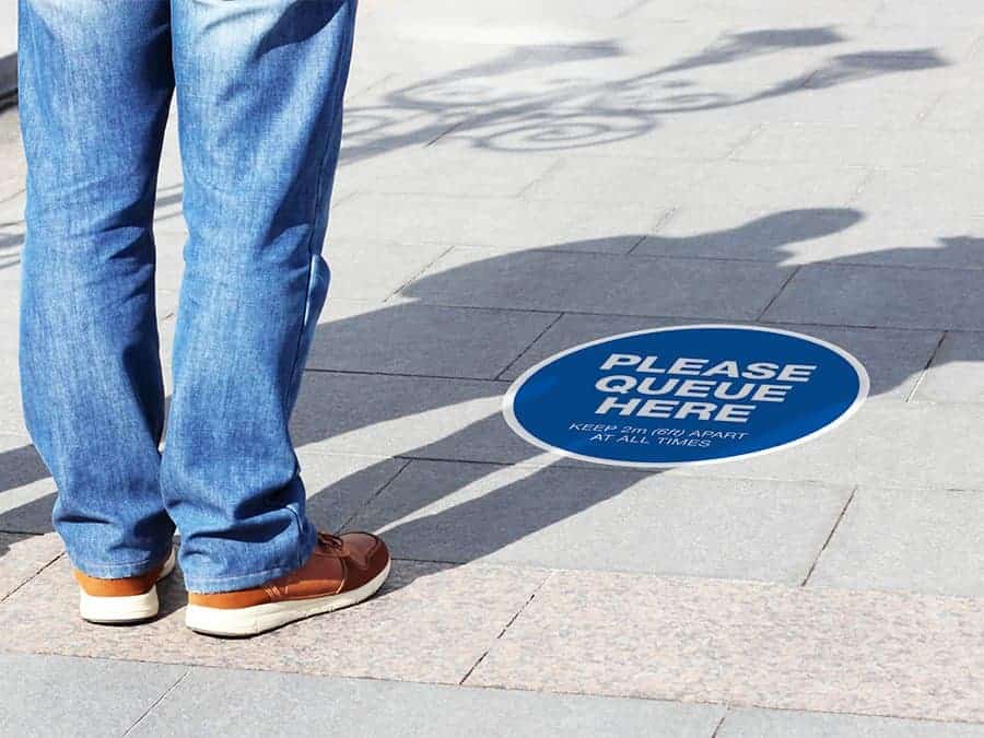 Social Distancing Sticker for outdoor usage that says "Stand apart keep your distance" on a paved ground