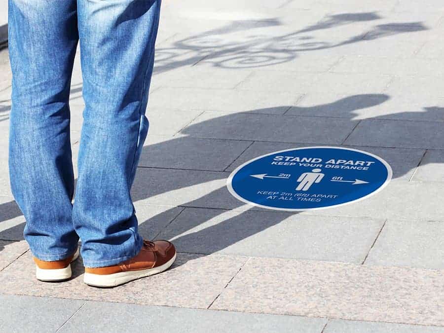 Social Distancing Sticker for outdoor usage that says "Stand apart keep your distance" on a paved ground