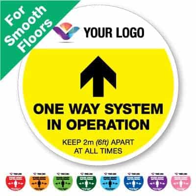 Round yellow Social Distancing Sticker for smooth floors branded with a logo that says "One Way System" on the top plus 8 other colours o the bottom