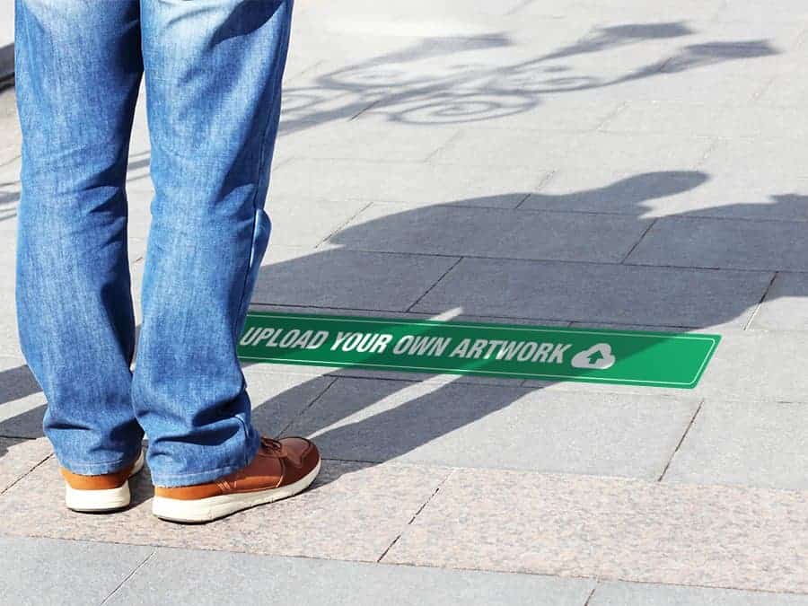 A long, rectangular and green and white social distancing sticker that says "upload your own artwork", on office carpet tiles