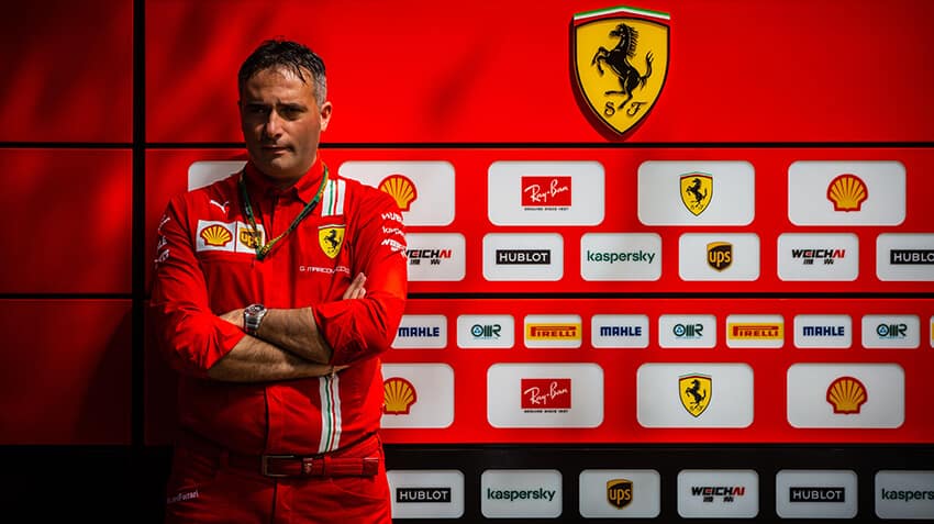 Mehcanic in Ferrari uniform standing in front of a wrapped garage wall